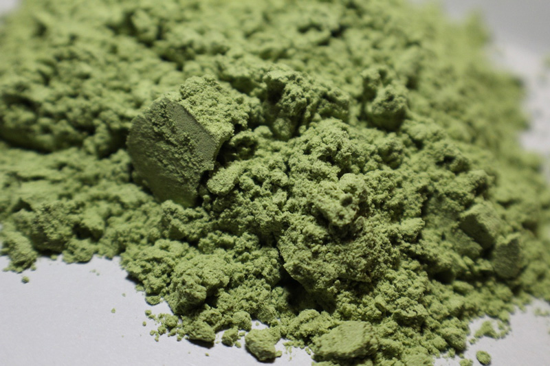 Green powder heaped on a smooth, light surface