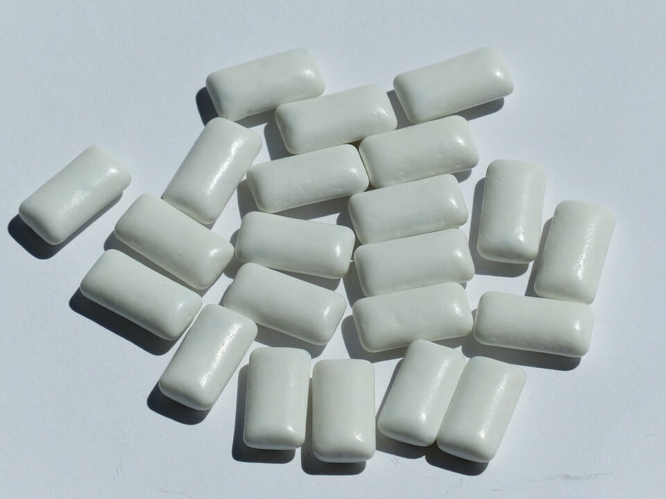 White chewing gum tablets on a white surface.